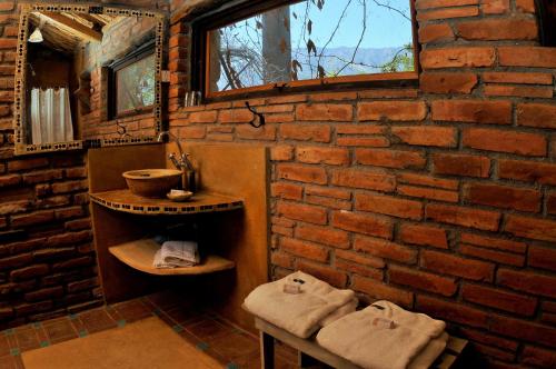 La salle de bains aux murs de briques est pourvue de 2 lavabos et de serviettes. dans l'établissement LAS JARILLAS Hostería & Bodega, à San Javier