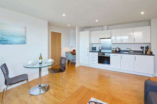 a kitchen and living room with a table and chairs at HQ Aparthotel Farnborough in Farnborough