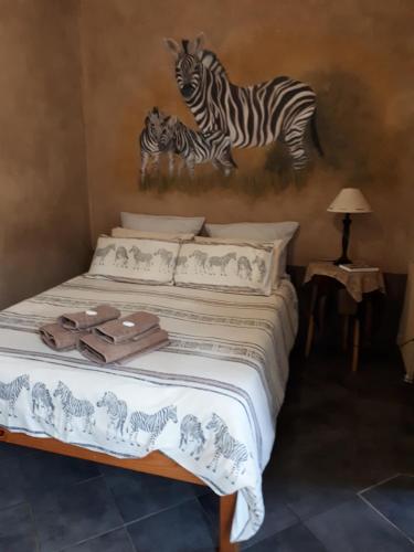 - une chambre avec un lit et 2 zèbres sur le mur dans l'établissement Vivian's Cottage, à Pretoria