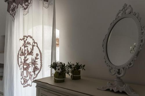 a mirror and flowers on a dresser in a room at Masseria Luco in Martina Franca