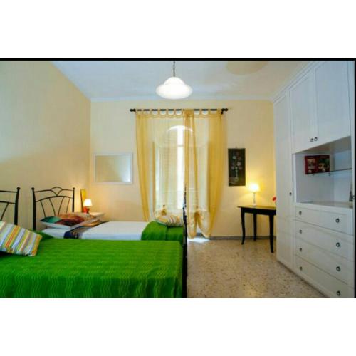 ローマにあるDomus Ines Roma San pietroのベッドルーム1室(緑のシーツとデスクが備わるベッド2台付)