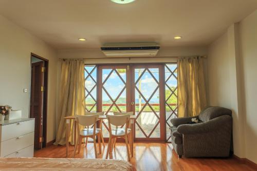 a living room with a table and chairs and a large window at Phuripimarn Penthouse in Pak Chong