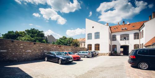 un grupo de autos estacionados en un estacionamiento al lado de un edificio en Adele Apartments, en Pécs