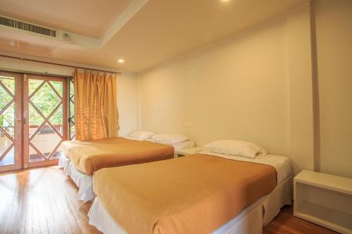 two beds in a room with a window at Phuripimarn Penthouse in Pak Chong