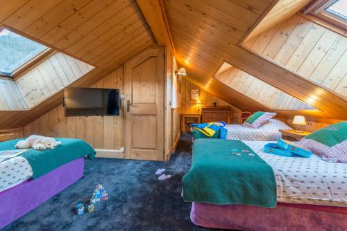 a attic room with two beds and a tv at Hotel Eterlou in Méribel