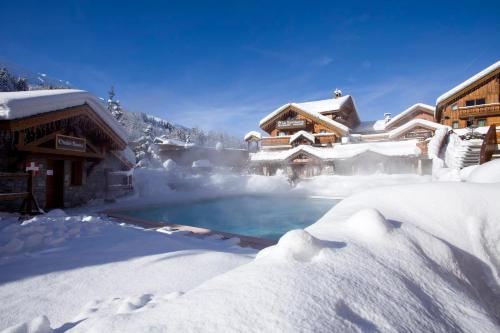 a house covered in snow with a swimming pool at Hotel Eterlou in Méribel