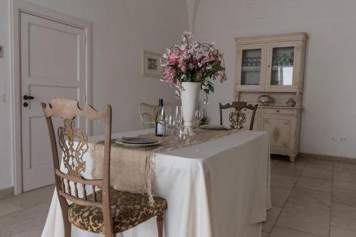 a dining room table with a vase of flowers on it at Masseria Luco in Martina Franca
