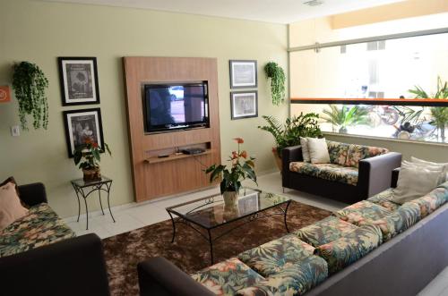 a living room with a couch and a tv at Hotel Concord in Campo Grande