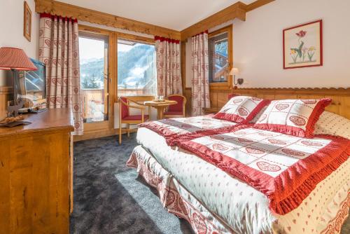 a bedroom with a bed and a desk and a window at Hotel Eterlou in Méribel