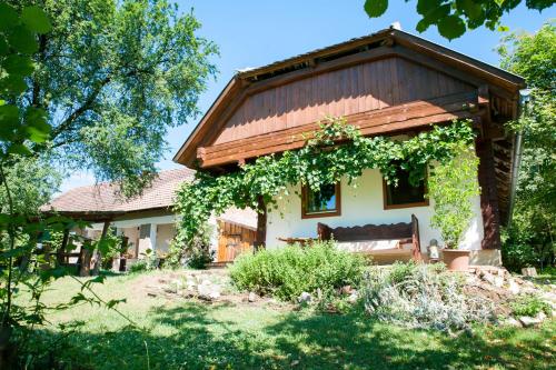 a house with a wooden roof and a bench at Fecskefészek Vendégház Őriszentpéter in Őriszentpéter