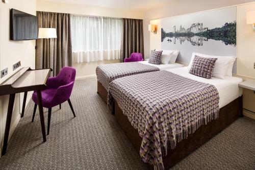 two beds in a hotel room with purple chairs at Mercure Swansea Hotel in Swansea