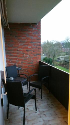 ヴィルヘルムスハーフェンにあるFerienwohnung Daisy 262のレンガの壁、バルコニー(椅子、テーブル付)