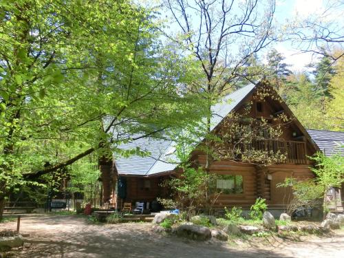 a log cabin in the woods with trees at Canadian Loghouse Inn AzuminoYujin in Azumino