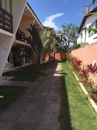 a walkway between two buildings with palm trees at Porto de Galinhas Duplex Rocha in Porto De Galinhas