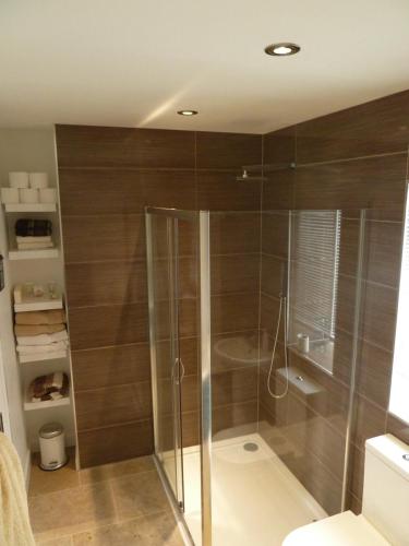 a bathroom with a shower with wooden walls at Plough Cottage in Bradfield