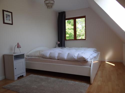 a white bedroom with a bed and a window at Uferschwalbe in Kopperby