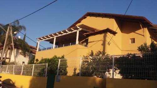 a yellow house with a fence in front of it at צימר ברחובות - Israeli Home in Rechovot