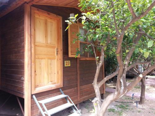 Cabaña de madera con puerta y silla al aire libre en Olympos Varuna Bungalows, en Olympos