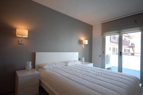 a bedroom with a white bed and a large window at Lets Holidays New Flat Beachfront In Castelldefels in Castelldefels