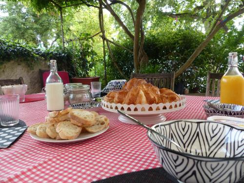 einen Tisch mit Teller mit Lebensmitteln auf einem roten und weißen Tischtuch in der Unterkunft Plume Et Pinceau in Montdragon