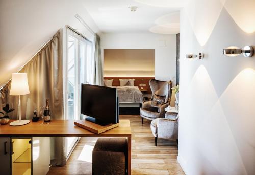 a living room with a television and a bedroom at Seevital Hotel & SPA - Ihr 4 Sterne Superior Hideaway direkt am See in Langenargen