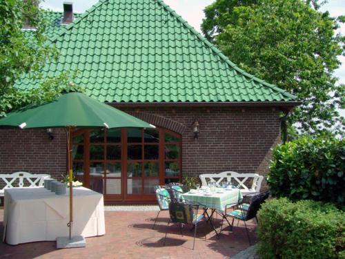a patio with a table and a green umbrella at Flair-Hotel Neeth in Lehmkuhlen