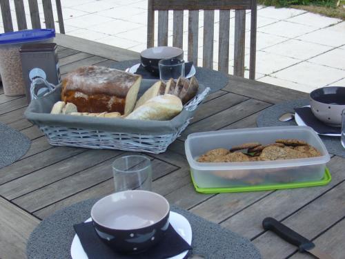 Una mesa con una bandeja de pan y cuencos de comida. en Le Jardin Ombragé, en Saint-Paul-dʼIzeaux