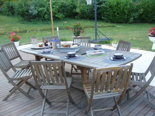 uma mesa de madeira com cadeiras e uma tigela de comida em Le Jardin Ombragé em Saint-Paul-dʼIzeaux