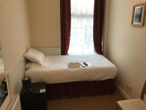 a small bed in a room with a window at The Island & Fairfield in Douglas