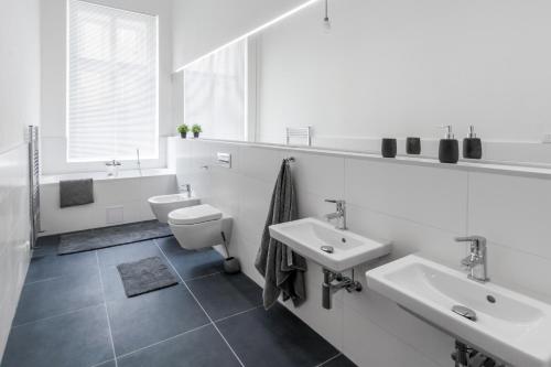 a white bathroom with two sinks and a toilet at Apartment Jindrisska in Prague