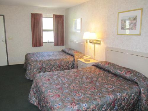 a hotel room with two beds and a lamp at Embassy Inn Motel Ithaca in Ithaca