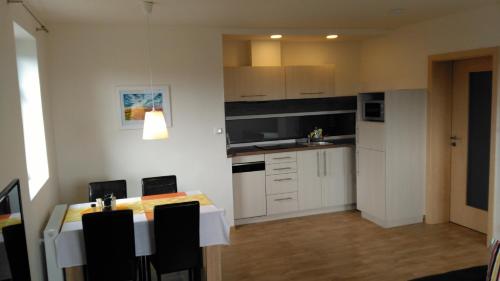 a kitchen with white cabinets and a table with chairs at APARTMÁNY NA VÝSLUNÍ in Horní Maxov
