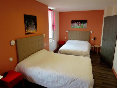 two beds in a room with orange walls at Hotel le Faisan in Saint-Avertin