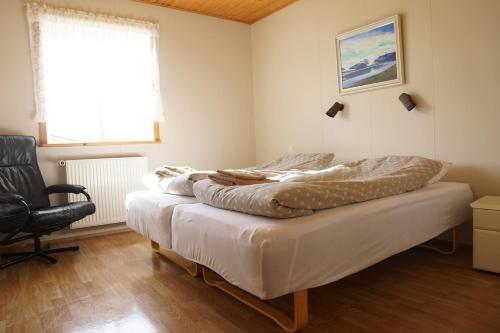 a bedroom with two beds and a chair at Hólmavað Guesthouse in Aðaldalur