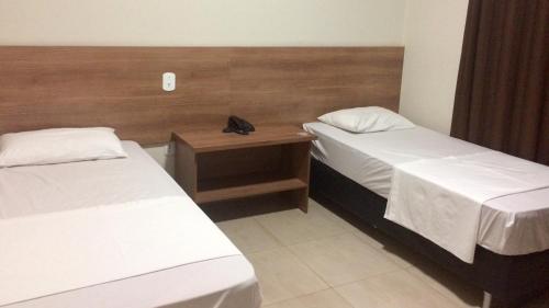 ein Hotelzimmer mit 2 Betten und einem Kopfteil aus Holz in der Unterkunft Cast Comfort Hotel in Paranaíba