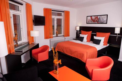a bedroom with a red bed and two red chairs at Hotel Harmonien in Haderslev