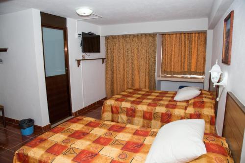 um quarto de hotel com duas camas e uma televisão em Hotel Symer em Chignahuapan