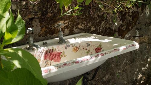 a sink with flowers on it sitting on a wall at Quinta das Leiras in Santo Tirso