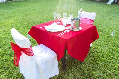 a red table with two white chairs and a table with wine glasses at Hotel Santa Cruz Huatulco in Santa Cruz Huatulco
