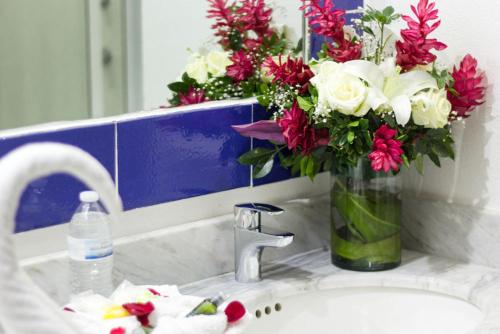 a vase of flowers sitting on a bathroom sink at Hotel Santa Cruz Huatulco in Santa Cruz Huatulco