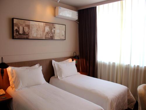 a hotel room with two beds and a window at JinJiang Inn Pingyang Taiyuan Road Hotel in Taiyuan