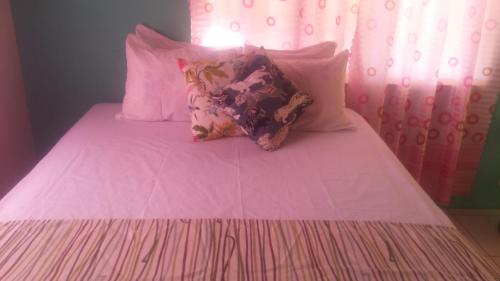 a pink bed with four pillows on top of it at G&R Guesthouse in Falmouth