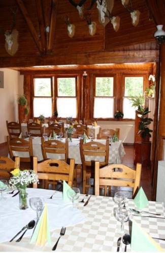 a dining room with tables and chairs and windows at Tapolca Fogadó in Miskolctapolca
