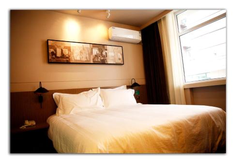 a bedroom with a white bed with a window at JinJiang Inn Pingyang Taiyuan Road Hotel in Taiyuan