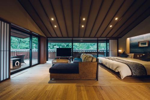 a bedroom with a bed and a couch and a television at Akariya Geihanro in Inuyama