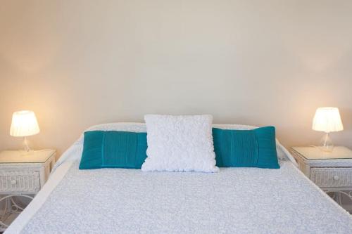 a bed with blue and white pillows and two lamps at Fremantle Local Beach Studio in Fremantle