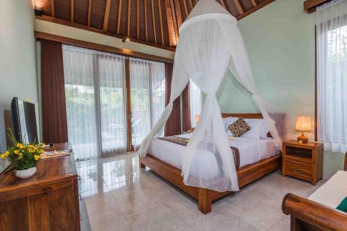 a bedroom with a bed with a mosquito net at Sweet Ginger Villa by Prasi in Ubud