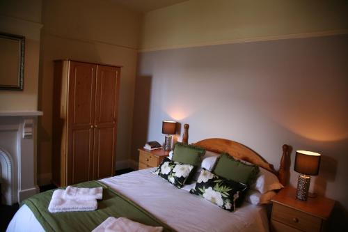 a bedroom with a bed with green sheets and pillows at Gillygate Guest House in York