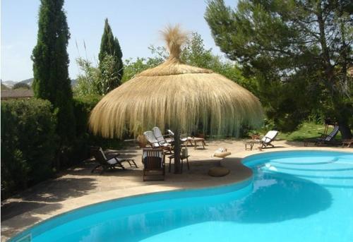 - un parasol et des chaises en paille à côté de la piscine dans l'établissement Son Mercadal, à Porreres