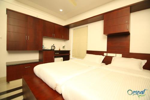 a bedroom with two white beds and wooden cabinets at Omnest in Cochin